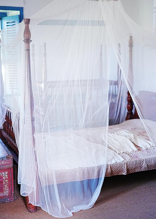 image of a bed with mosquito netting and night clothes at the Baldwin Home Museum. 